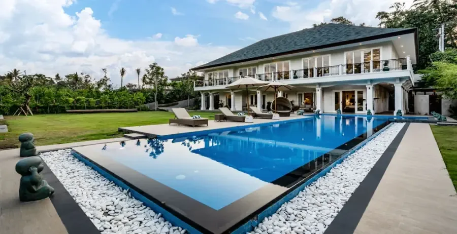 Two-storey Balinese luxury villa beside a long blue swimming pool